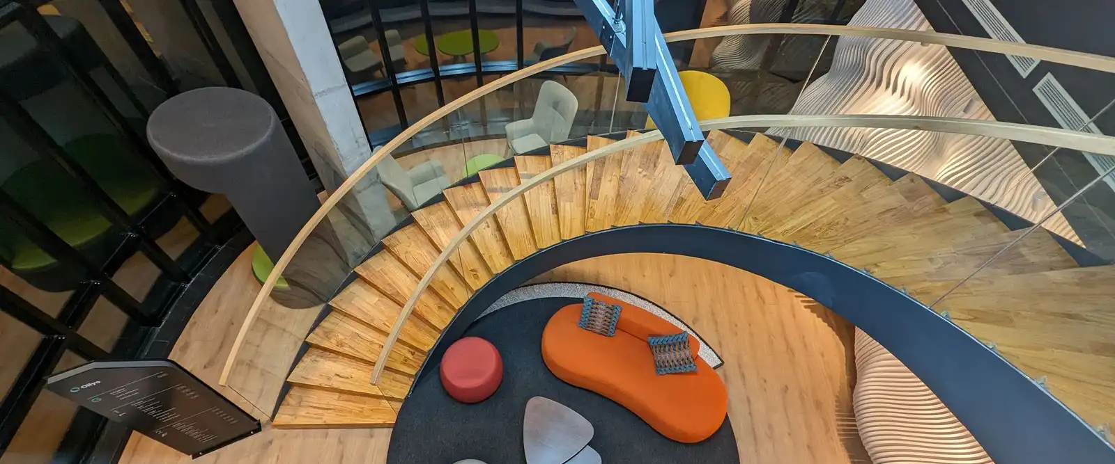 A spiral staircase seen from above, curving down to a lounge with round seats