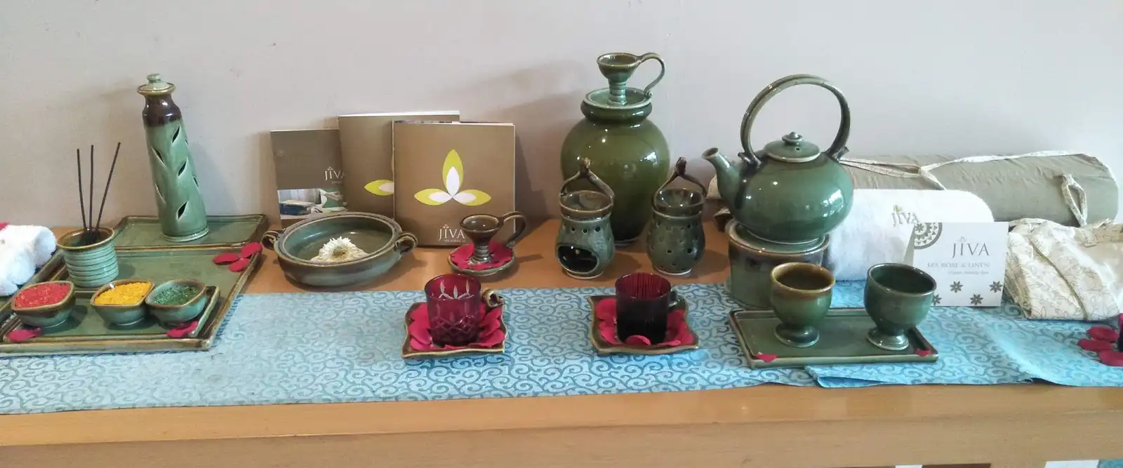 Green ceramic teapots, cups and small dishes laid out on a table